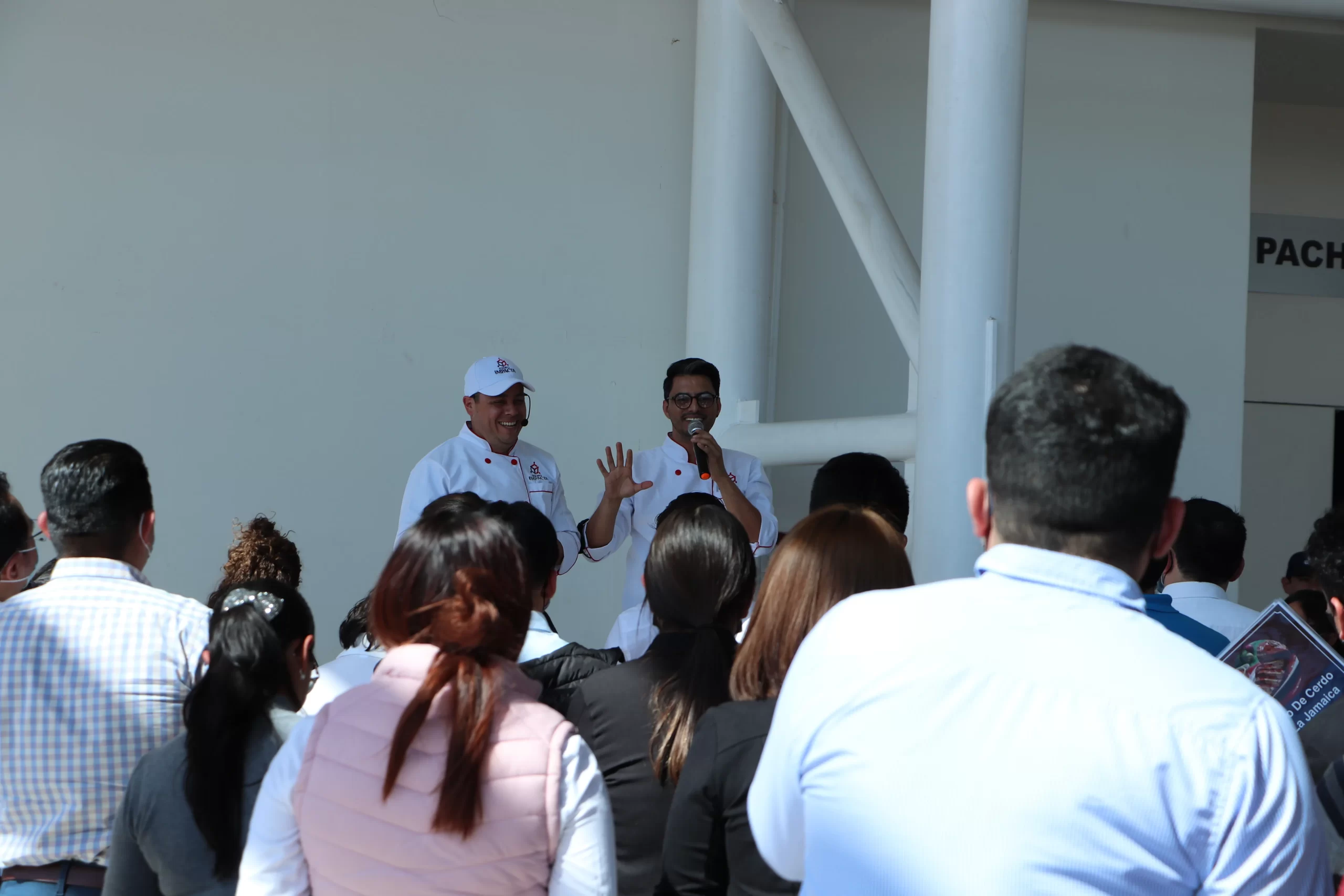Ejemplo de cómo los facilitadores de Equipo Impacta guían las dinámicas de integración laboral en las empresas. Dinámicas de integración laboral: Fotografía de una persona hablando por micrófono a un grupo de personas.