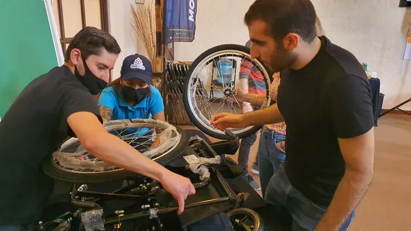 Foto de dos hombres y una mujer trabajando la retención de talento mientras arman un silla de ruedas