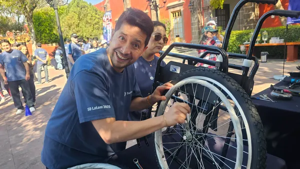 Foto de hombre sonriente por la retención de talento de Equipo Impacta mientras arma una silla de ruedas