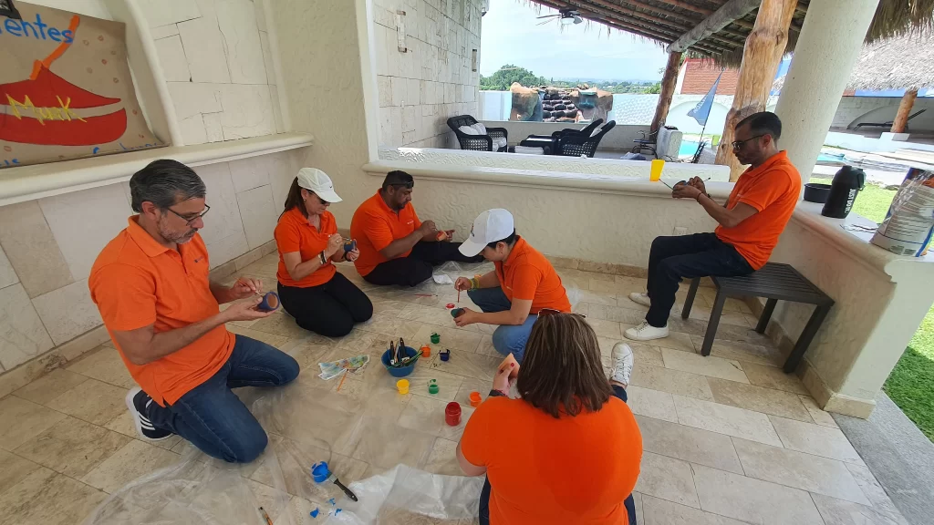 Fotografía de Compañeros vestidos de naranja sentados practicando el wellness corporativo de Equipo Impacta