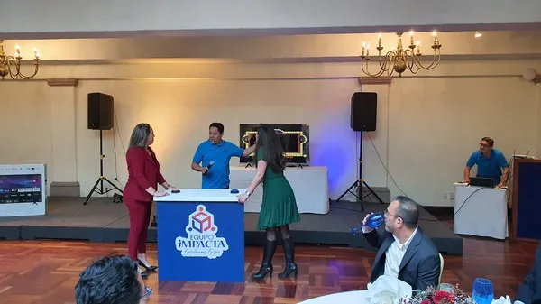 Dos mujeres paradas una frente a la otra en un evento empresarial realizando dinámica 100 mexicanos dijeron juego de preguntas.