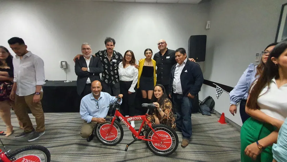 Equipo de trabajo junto a una bicicleta roja durante dinámica para aprender cómo evitar el estrés laboral.