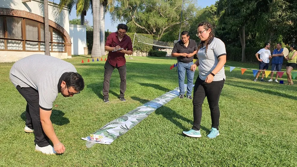 Tres hombres y una mujer al aire libre participando en una actividad para saber cómo motivar a mis colaboradores.