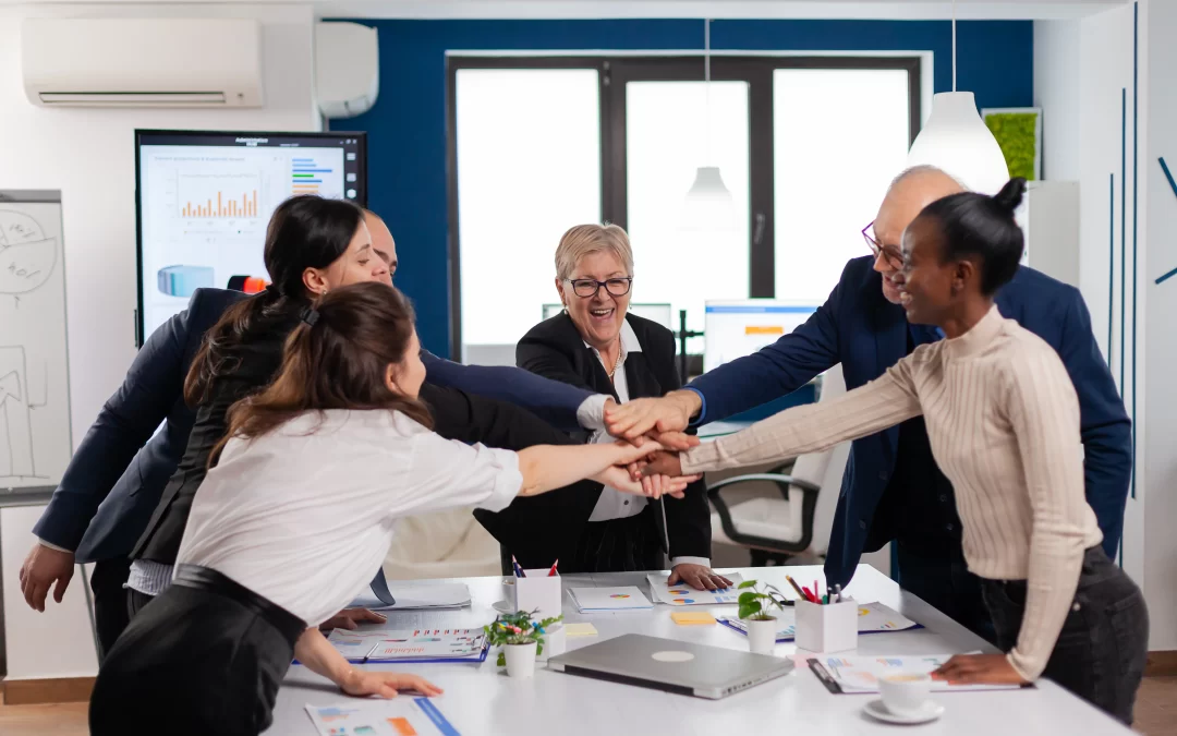 Fotografía de grupo de personas juntando manos al centro mejorando su trabajo gracias a fortalezas de un equipo de trabajo.