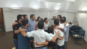 Fotografía de colaboradores reunidos en un abrazo en círculo después de corregir la victimización en equipos de trabajo.