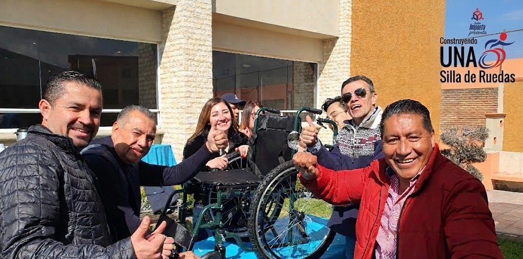 Fotografía de frente de colaboradores de una empresa después de haber hecho la construcción silla de ruedas.