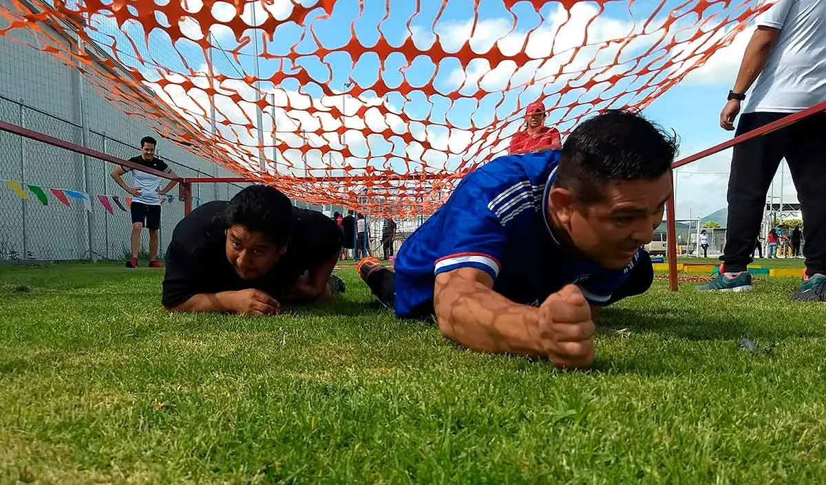 Fotografía de dos colaboradores avanzando en el pasto durante una actividad que es parte de rally de integración.