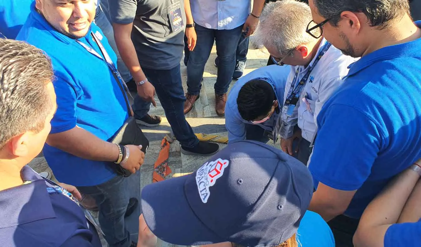 Fotografía de un grupo de colaboradores con camisa azul realizando actividad de Rally de integración.