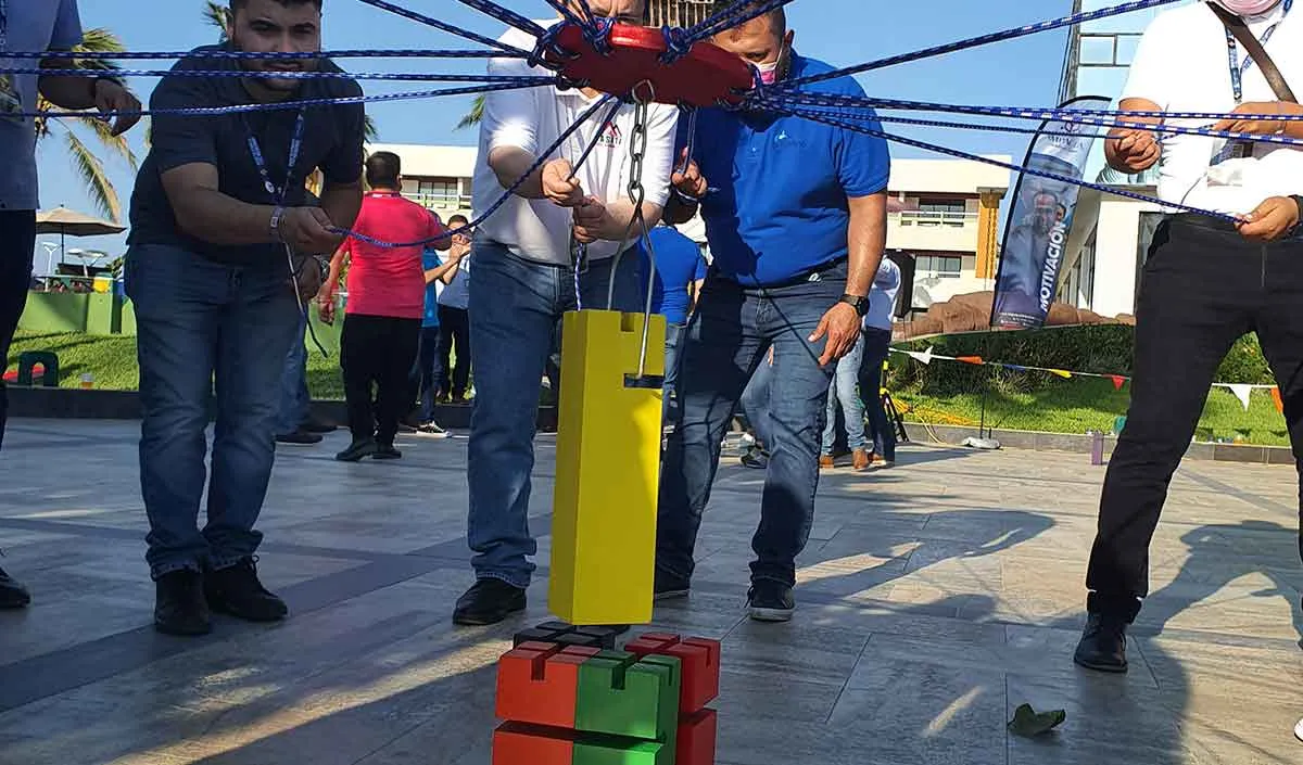 Fotografía de colaboradores tirando las cuerdas de una figura color amarillo durante actividad de rally de integración.
