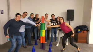 Cómo mejorar el clima laboral en una empresa: Fotografía de un grupo de personas alrededor de una torre de colores.