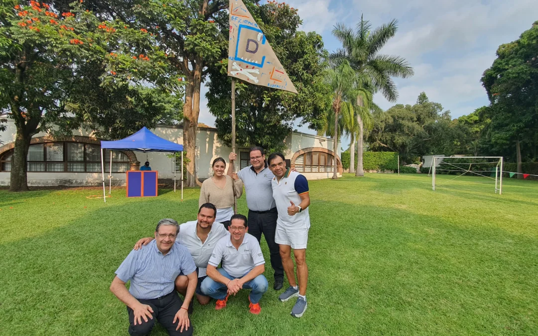 Integración empresarial: Fotografía de personas de pie al ire libre sobre el pasto sosteniendo una bandera color café.