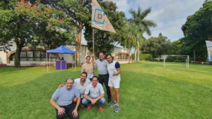 Integración empresarial: Fotografía de personas de pie al ire libre sobre el pasto sosteniendo una bandera color café.